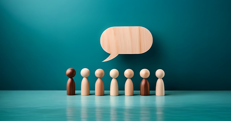 TimeMgmt_5 • Roche Leadership Wooden figures beneath a wooden speech bubble symbolizing group communication.
